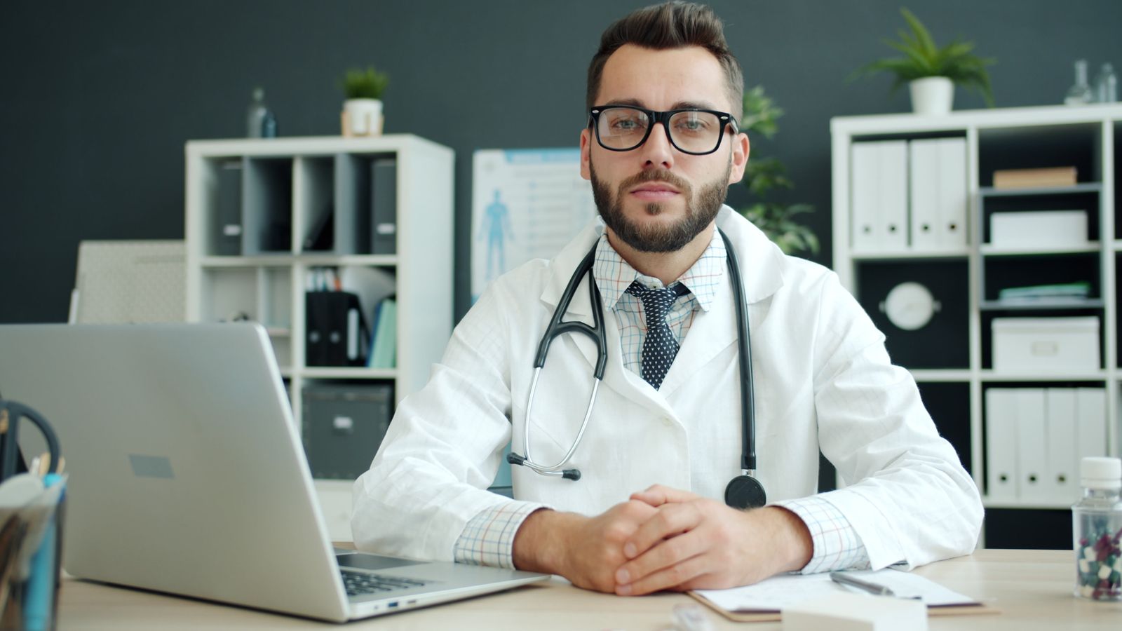 Médico de jaleco sentado à mesa do consultório